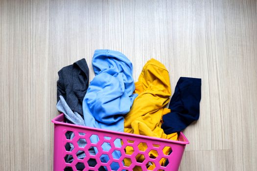 Clothes in pink plastic laundry basket. Top view