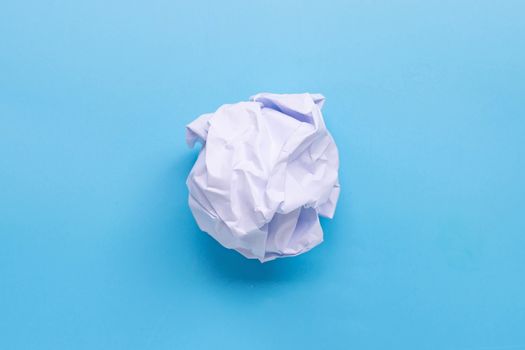 Crumpled paper ball on blue background. Top view