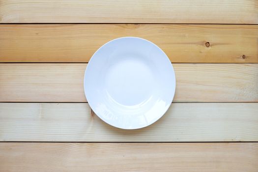 Empty white ceramic plate on wooden background. Copy space