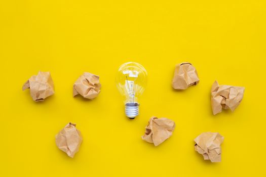 Light bulb  with brown crumpled paper ball on yellow background. Top view