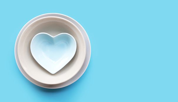 Stack of dish and bowl on blue background. Copy space
