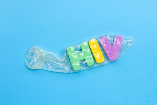 Condom with "HIV" alphabet on white blue background. Copy space