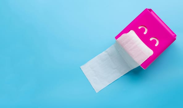 Pink tissue paper box on blue background. Copy space