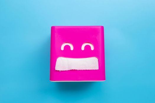 Pink tissue paper box on blue background. Copy space