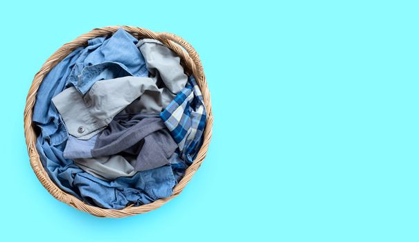 Clothes in laundry basket on blue background. Copy space