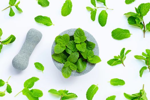 Mint leaves in stone mortar and pestle on white background. Top view