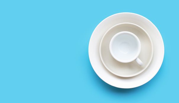 Stack of dish, bowl and cup on blue background. Copy space