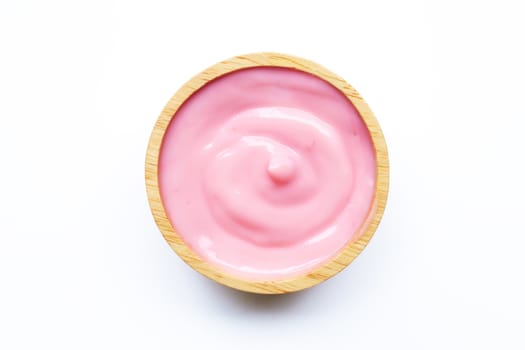 Pink strawberry yogurt in wooden bowl on white background.