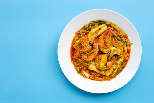 Fried seafood with curry powder on blue background. Copy space