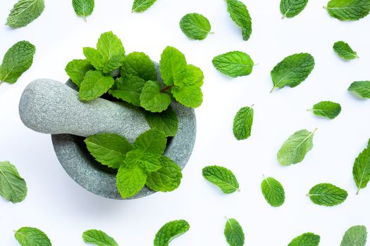 Mint leaves in stone mortar and pestle on white background. Top view