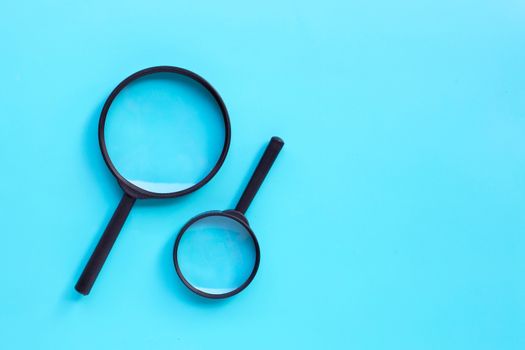 Magnifying glass on blue background. Top view