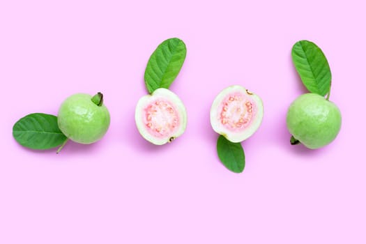 Top view of fresh ripe guava and slices with leaves on pink background. Copy space