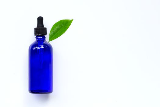 Essential oil bottle with green leaf on white background. Copy space
