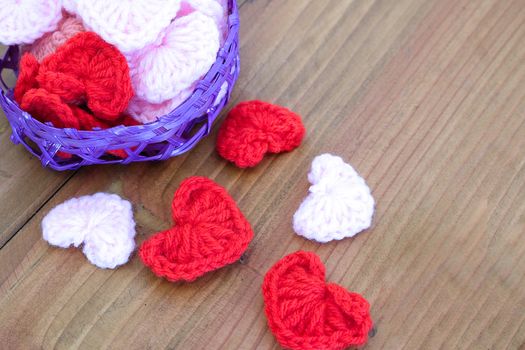 little white, pink, and red handmade wool hearts in a purple bamboo basket on a wooden table, love, romance, anniversary, Valentines' Day