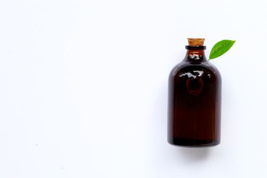 Essential oil bottle with green leaf on white background. Copy space