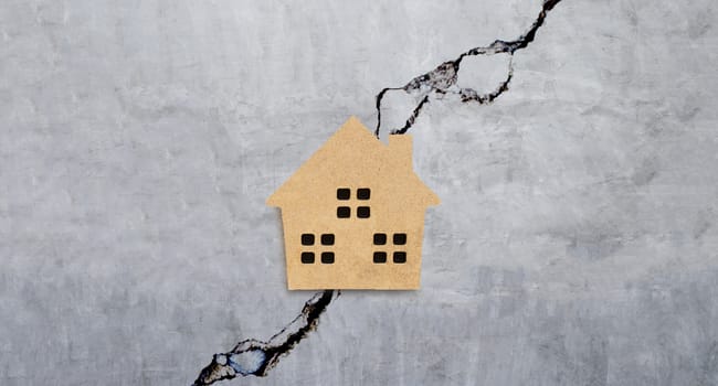 Miniature house on cracked cement wall texture background. Top view