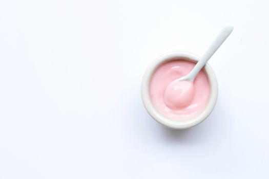 Ceramic bowl of  pink strawberry yogurt on white background.