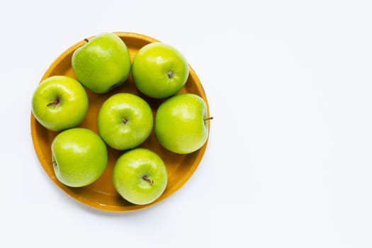 Fresh green apples on yellow plate on white background. Top view