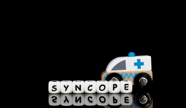 Alphabet letters spelling a word syncope with a model ambulance in the background. Medical emergency concept