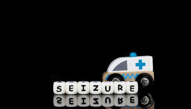 Alphabet letters spelling a word seizure with a model ambulance in the background. Medical emergency concept