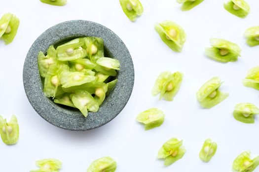 Moringa oleifera seeds in stone mortar on white background. 