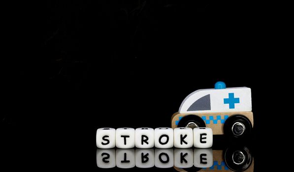 Alphabet letters spelling a word stroke with a model ambulance in the background. Medical emergency concept
