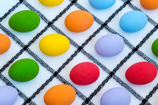colorful easter eggs on black and white checker cloth background, top view