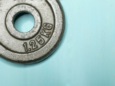 closeup image of a metal weight plate on wooden background. Exercise concept.