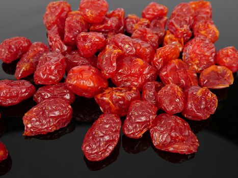 a heap of colorful dry cherry tomatoes on black background