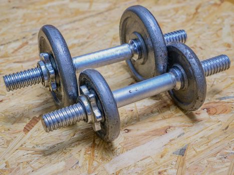 closeup image of a pair of metal dumbbells on wooden background. Exercise concept.