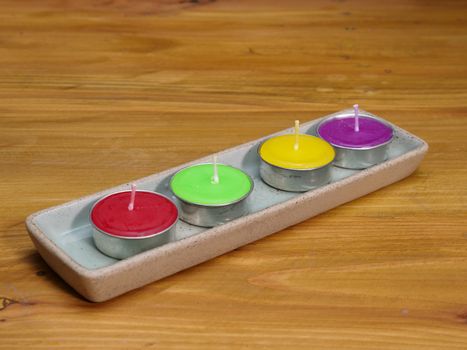 colorful hademade natural wax candles on a ceramic plate, wooden background