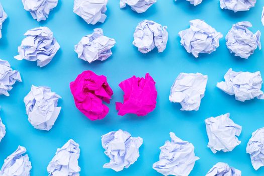 White with pink crumpled paper balls on a blue background. Top view
