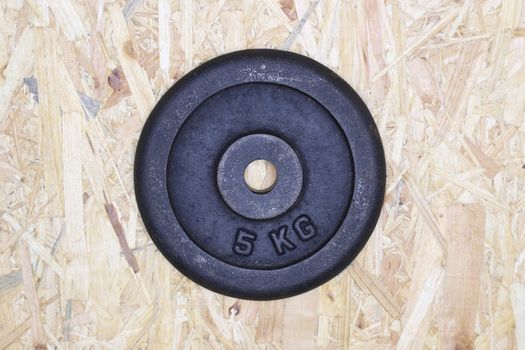 a 5 kilogram weight plate, isolated on wooden background
