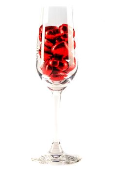 bright red heart-shaped candies in a clear tall glass, white background