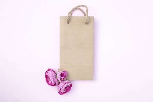 brown paper bag with natural coconut straw handles and beautiful purple pink flowers. Template mockup for putting your loco or illustraion. Top view, isolated, light background