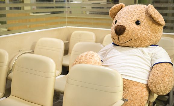 a life size stuffed toy bear sitting at a nonspecific waiting area