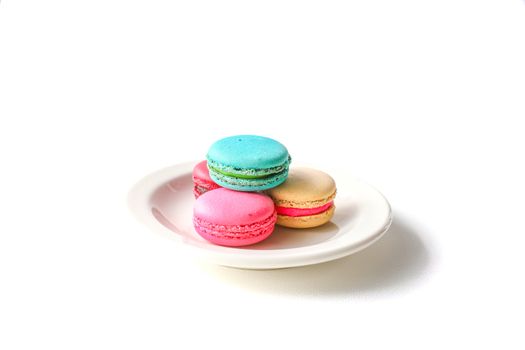 colorful macaroons on a white ceramic plate, isolated on white background