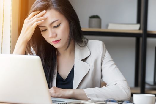 young Asian stress woman at work, depressed woman in the office. portrait of beautiful young Asia female feeling sick, having headache, office syndrome. healthcare at work place concept