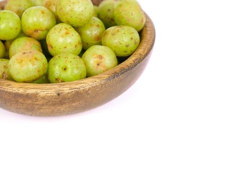 fresh indian gooseberry in a teak bowl, isolated on white background