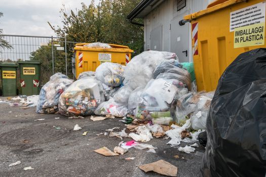 Piles of garbage on the streets due to fulls garbage bins. Incivility, rudeness and dirt. Bergamo, ITALY - October 15, 2018