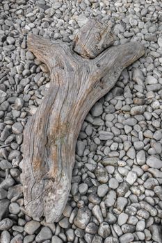 Wood carved statue of crucified Jesus Christ. Strange artistic statue. The sculpture is lying on white pebbles.