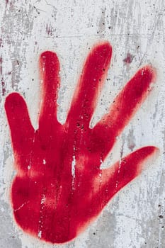 The symbol of a red hand painted with spray on the wall.
