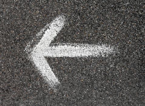 Arrow drawn on the asphalt with a paint brush. Concept of direction.