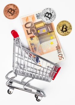 Shopping cart with bitcoin and banknote on white. Financial concept.