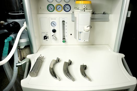 an anesthetic machine in the operation room with a set of laryngoscope and blades ready for intubation