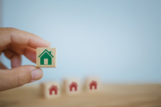 Home loan, home for rent, financial concept : Hand chooses wooden cube blocks are different with home icons. depicts renter who want to own asset for better standard of living.