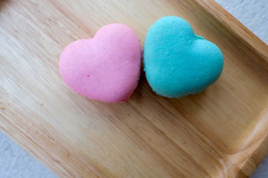 pink and blue heart-shaped macaroons on a wooden tray