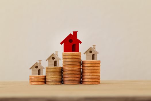 Arrange red outstanding small house or home on stacks of coins, Property investment real estate / Home loan / asset refinancing concept : depicts a homeowner or a borrower turns properties into cash.