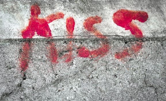 The word KISS on grungy wall. Faded colors.