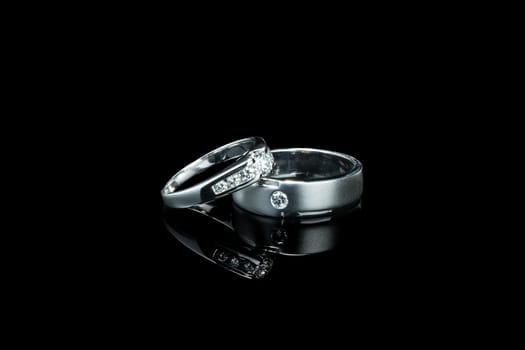 couple of luxury wedding diamond rings for bride and groom isolated on black background with shadow reflection and copy space. couple ring for wedding and engagement ceremony concept